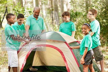 Students pitching tent with teacher