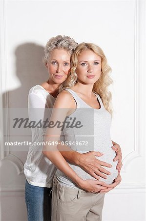 Woman holding pregnant daughters belly