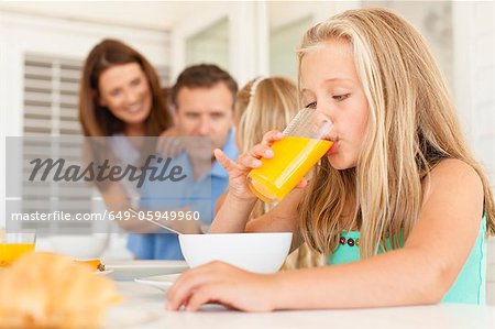 Girl drinking orange juice at breakfast