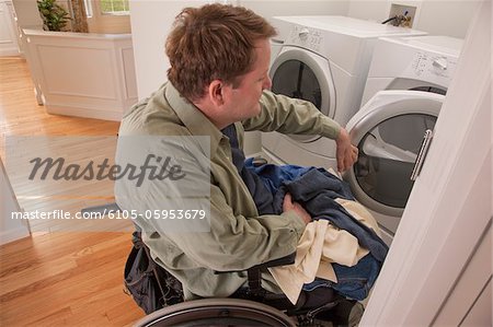 Mann mit Querschnittslähmung im Rollstuhl seine Wäsche zu Hause