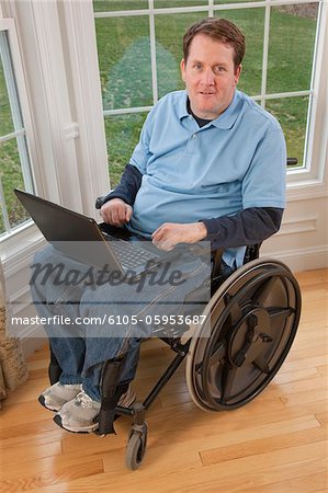 Homme d'affaires avec une lésion médullaire en travaillant sur un ordinateur portable avec mains handicapés fauteuil roulant