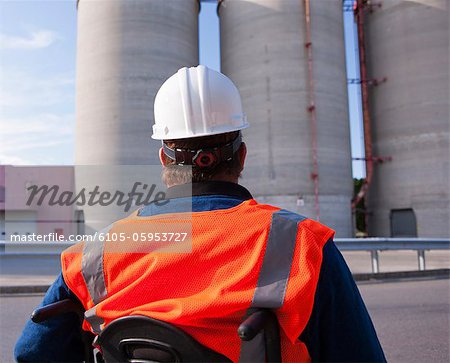 Facilities engineer in a wheelchair inspecting outdoor bulk storage tanks