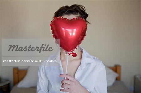 Jeune femme avec coeur en forme de ballon en face de son visage