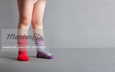 Child wearing one red sock and one striped sock