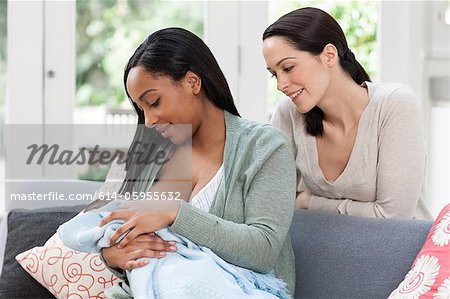 Young woman watching friend breastfeed her baby