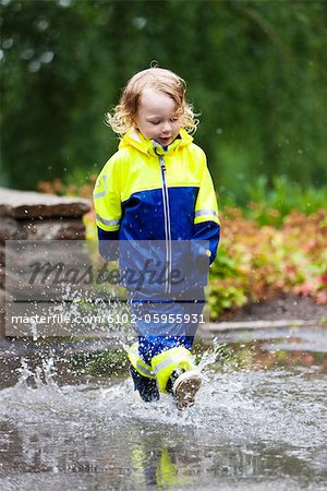 Boy walking in puddles in park