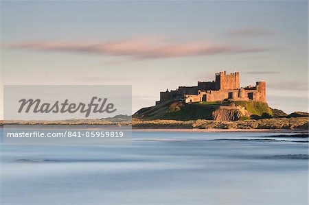 Bamburgh Castle gebadet im goldenen Abendlicht über Bamburgh Bucht mit dem Meer füllen das Vordergrund, Northumberland, England, Vereinigtes Königreich, Europa