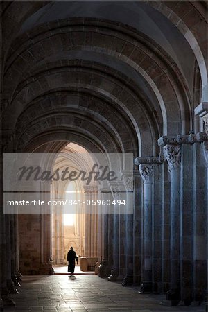 Interior north nave aisle with priest walking away, Vezelay Abbey, UNESCO World Heritage Site, Vezelay, Burgundy, France, Europe
