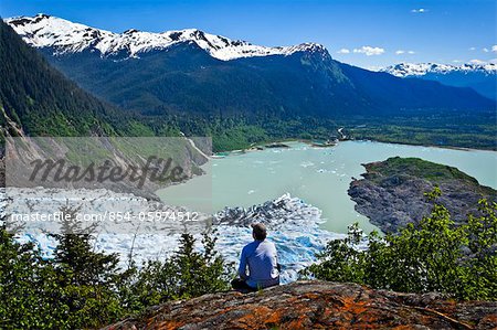 A male hiker looking down onto Mendenhall Glacier and Mendenhall Lake from West Glacier Trail, Juneau, Southeast Alaska, Summer