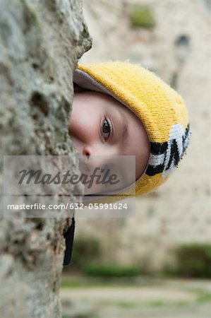 Boy peeking from behind tree