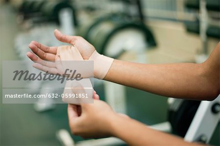 Woman wrapping hand with bandage, cropped