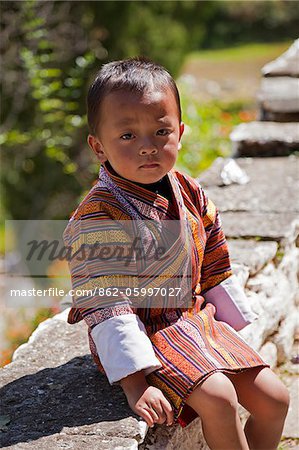 Timide petit garçon dans un gho très intelligent en attente de bénédictions à Trongsa Dzong.
