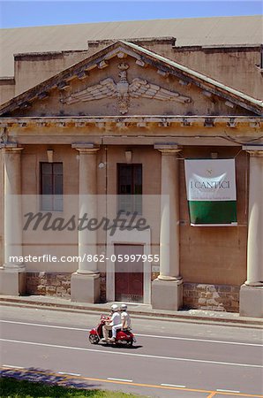 Italien, Toskana, Lucca. Eine stilvolle 30er Jahre Gebäude im historischen Zentrum und ein paar auf einen Roller vorne schnell vorbei