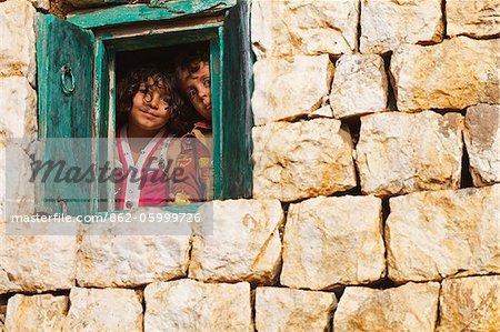 Jemen, Sana ' a Haraz-Gebirge der Provinz Al-Hajjarah. Kinder schauen durch die Fenster ihres Hauses.