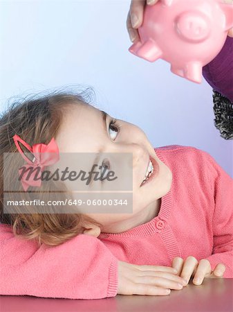 Smiling girl examining piggy bank