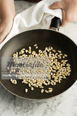 Chef toasting pine nuts in pan