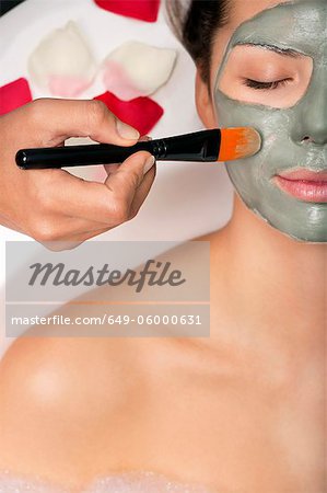 Woman having skin mask applied in bath