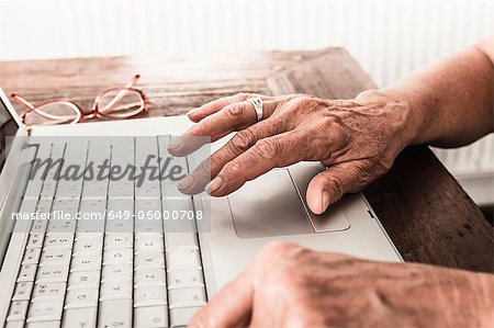 Close up of older mans hands on laptop