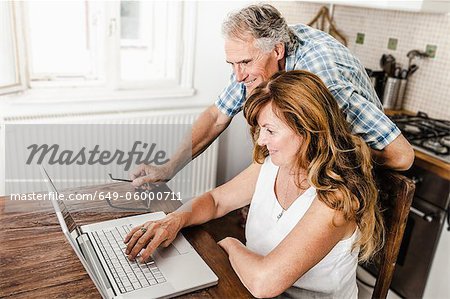 Older couple using laptop in kitchen
