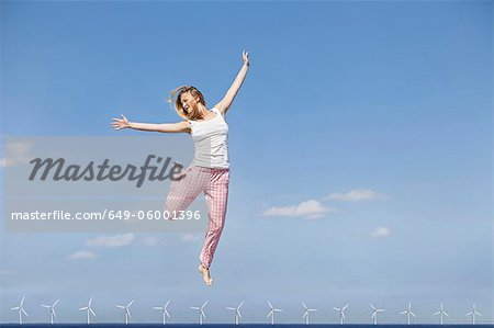 Woman jumping for joy over wind turbines