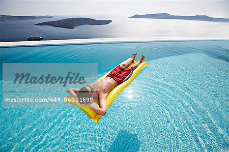 Adolescent reposant sur radeau en piscine