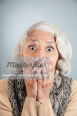 Portrait de femme senior couvrant la bouche avec des mains en studio