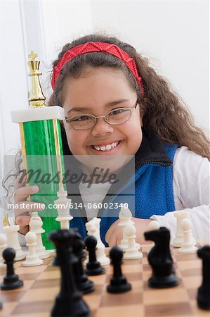 Portrait of young girl holding chess trophy