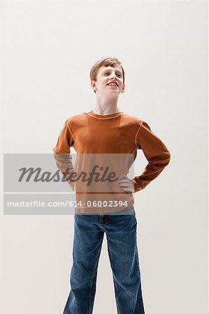 Boy in brown sweater in superhero stance, studio shot