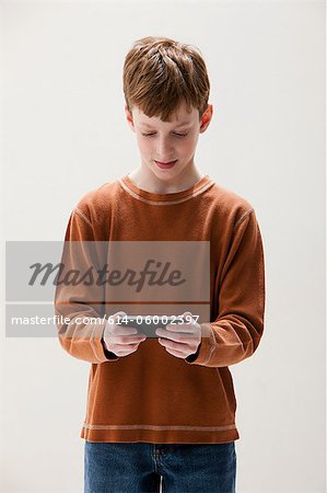 Boy in brown sweater playing hand held video game, studio shot