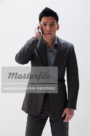 Young Asian businessman using cellphone, studio shot