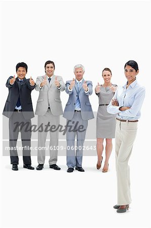 Multicultural business team with their thumbs-up with a smiling woman in foreground against white background