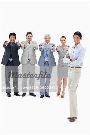Multikulturellen Business-Team mit ihren Daumen nach oben mit einer Frau im Vordergrund vor weißem Hintergrund