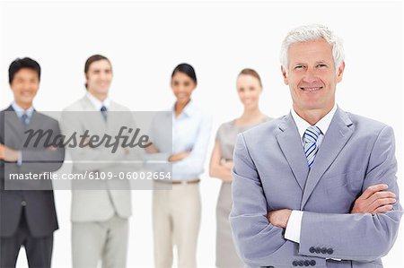 Close-up of a smiling multicultural business team with their arms folded focus on a white hair man in foreground
