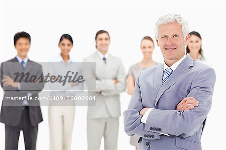Close-up of a multicultural business team crossing their arms focus on a smiling mature man in foreground