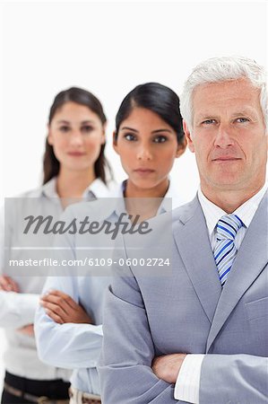 Close-up of a business man with two women behind him against white background