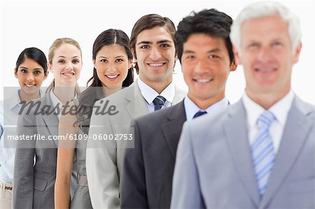Close-up of smiling business people in a single line with focus on the fourth person against white background