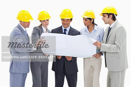 Gens d'affaires portant des casques de sécurité en regardant une carte sur fond blanc