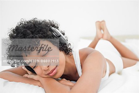 Woman listening to music with her eyes closed while lying on her bed