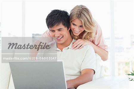 Un homme est assis et l'utilisation de l'ordinateur portable que la femme lui de montres à côté de sa tête.