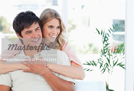 A man and woman are looking to the side as they hold hands and embrace.