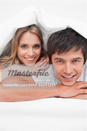 Un plan d'un homme et une femme à la fin du lit en souriant et se reposer sur leurs mains rapproché.