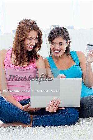 Happy young women sitting down with a laptop while shopping on internet