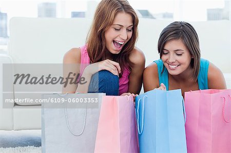 Laughing teenage looking at purchase bags accompanied by a friend