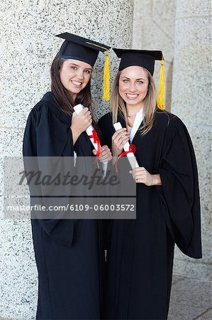 Jeunes filles finissants tendant fièrement leur diplôme tout en affichant un grand sourire