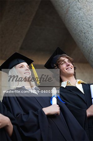 Low-angle view of happy graduating students holding their diplomas