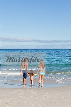 Jeune famille marchant vers la mer sur la plage