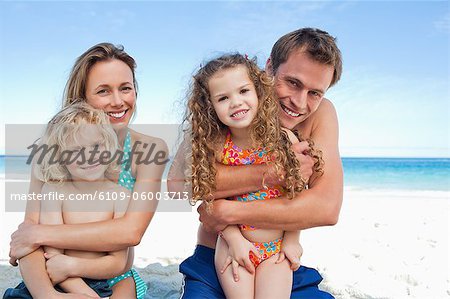 Parents on the beach hugging their little children