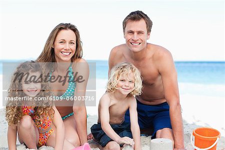 Fröhliche Familie bauen eine Sandburg am Strand