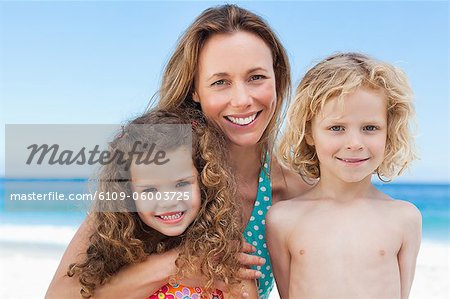 Mère souriante avec ses enfants sur la plage