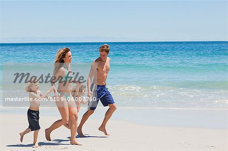 Vue latérale d'une jeune famille, marchant le long de la plage